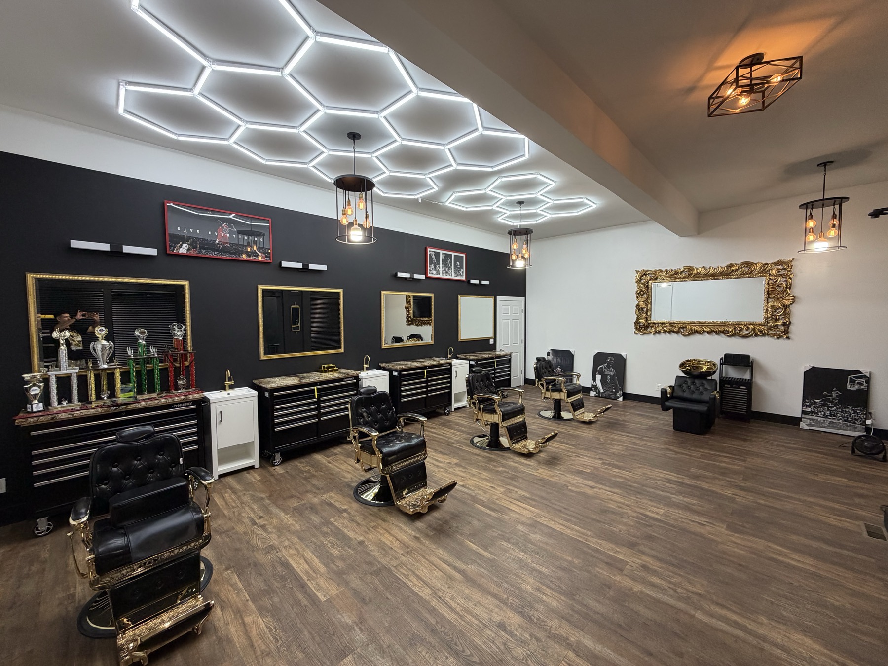 Inside X Express Barbershop Studio — gold-trimmed barber chairs under hexagon LED lighting
